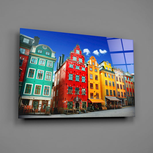 Stockholm Old Town houses glass wall art on a plain gray wall, angled to show the glossy surface