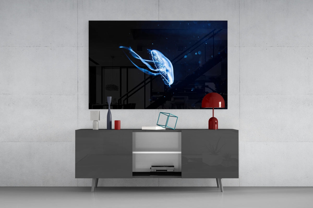 Glowing blue jellyfish glass wall art above a dark gray sideboard with a small red lamp
