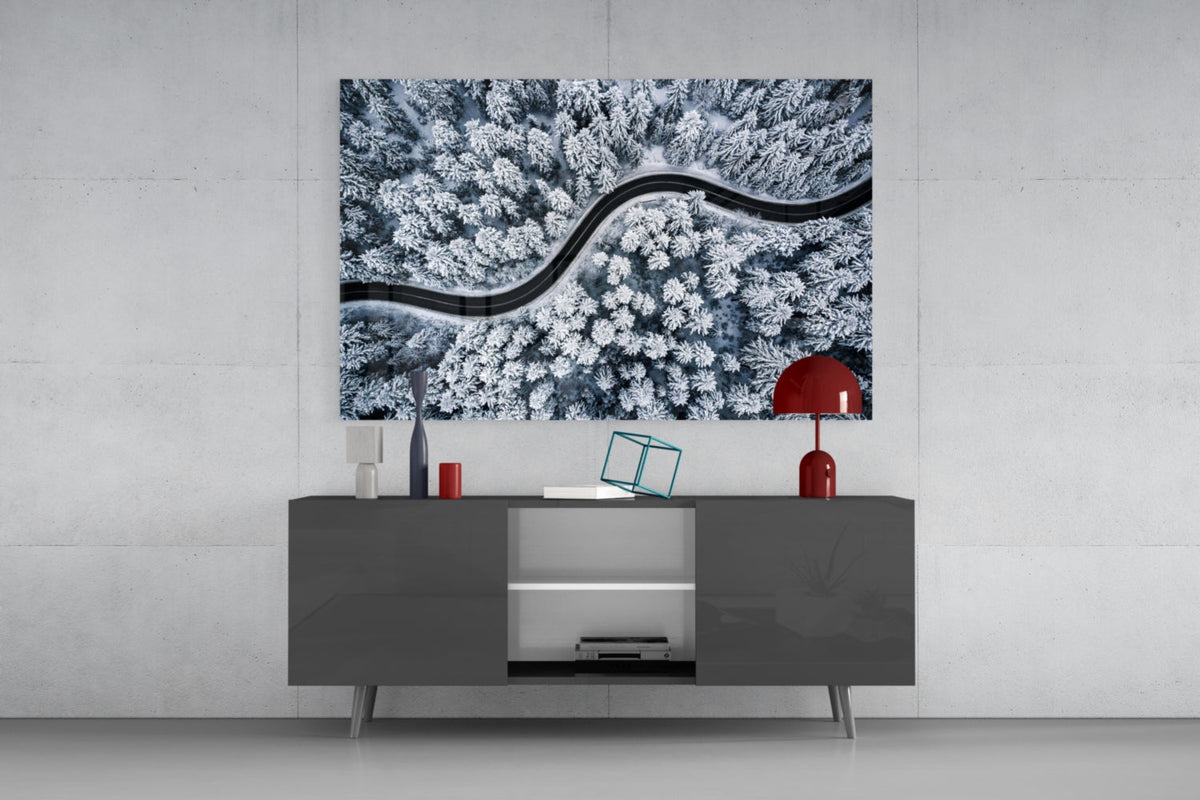 Icy blue snowy forest road glass wall art above a dark gray sideboard with a red table lamp