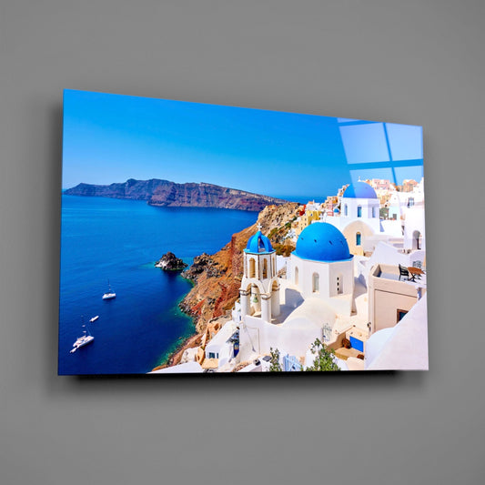 Santorini blue domes glass wall art on a gray wall, light reflecting off the glossy front