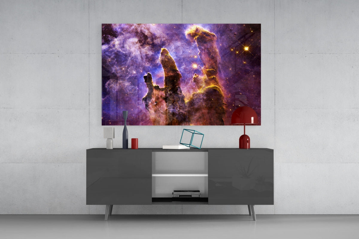 Lilac and gold nebula pillars glass wall art above a dark gray sideboard with a red lamp on a concrete wall