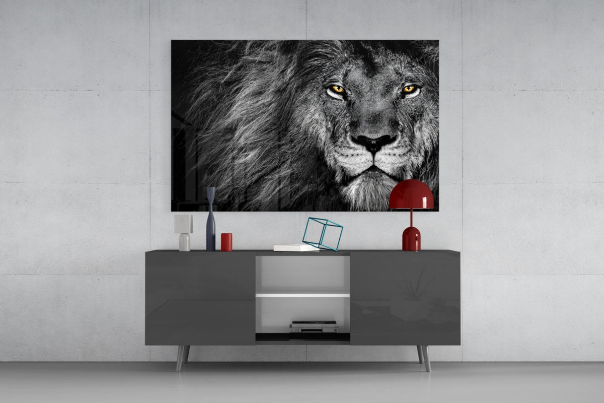 Black and white lion glass wall art above a dark gray sideboard with a small red lamp