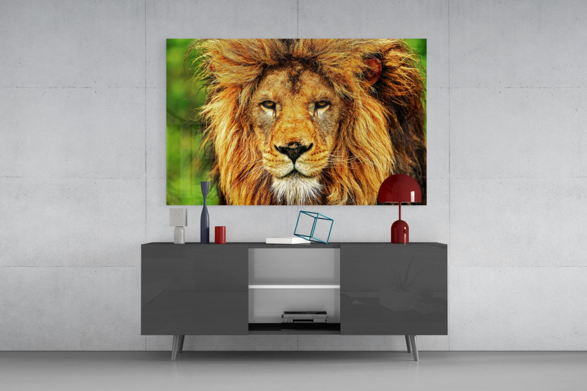 Lion portrait on green glass wall art above a dark gray sideboard with a small red lamp