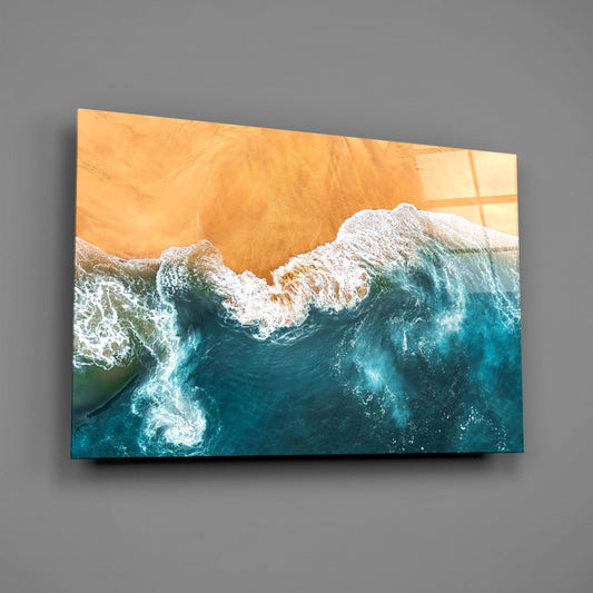 Amber sand beach waves glass wall art on a gray wall, light reflecting off the glossy front