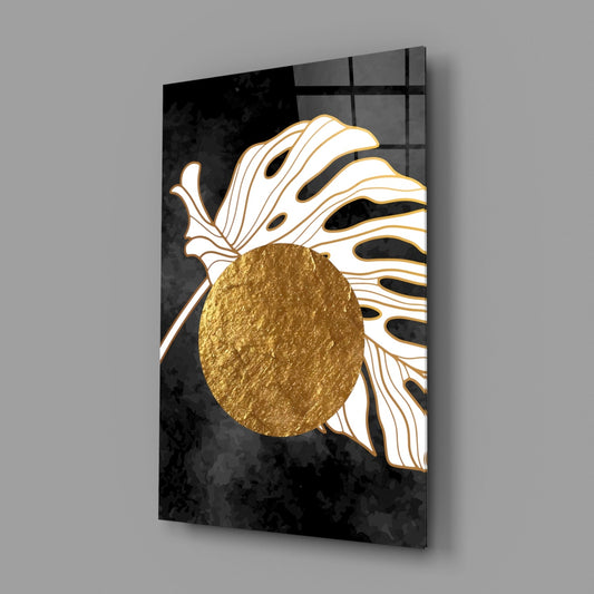 Monstera and gold circle glass wall art on a gray wall, light reflecting off the glossy front