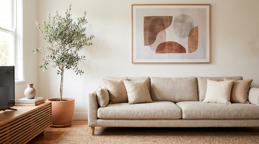 Framed horizontal abstract print hung at about two-thirds the width of a neutral linen sofa, showing correct wall art size above a couch