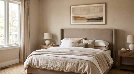 A single horizontal framed abstract print above an upholstered headboard, sized to about two-thirds the bed width, showing correct scale and height above a bed