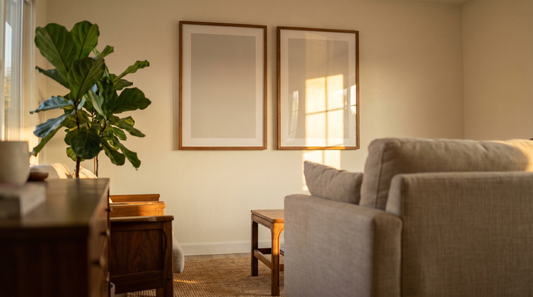 Matte vs glossy art prints compared side by side on a sunlit living room wall, one soft and glare-free, one shiny and reflective