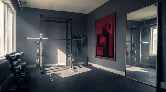 Home gym wall art ideas: a bold framed print and a large mirror facing a squat rack in a dark, energetic workout room