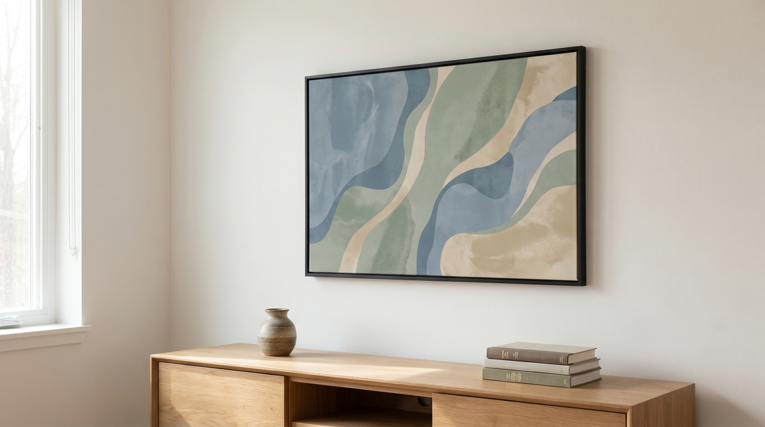 Motivational wall art ideas in a calm modern living space: one large framed abstract print in muted blue and sand tones above a low wood console