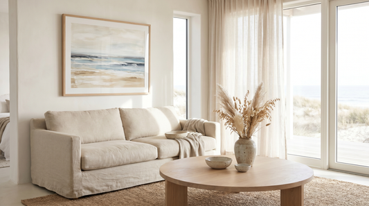 Airy modern coastal living room in muted blue, sand, and warm white with a large framed abstract horizon print over a linen sofa