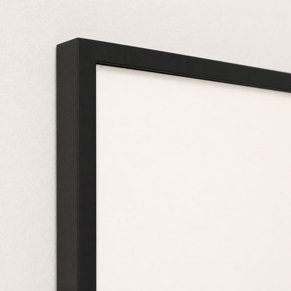 Close-up of the black frame corner against the off-white print, showing the moulding profile and depth