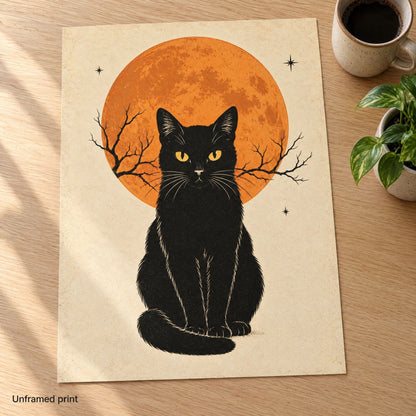 Unframed vintage black cat print on matte paper, lying flat on an oak desk beside a mug