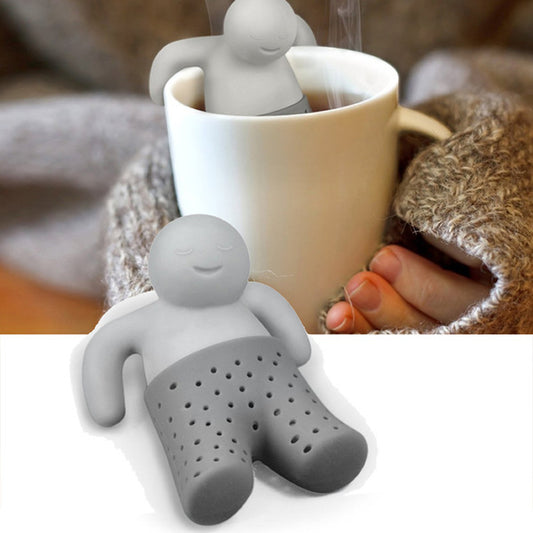 Gray person-shaped tea infuser in a white mug with steam, held by a hand.