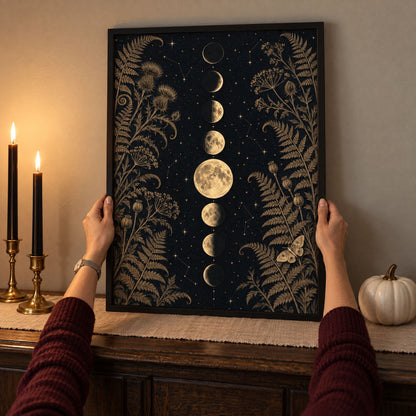 Framed black and gold moon print being set on an October dining sideboard between black taper candles