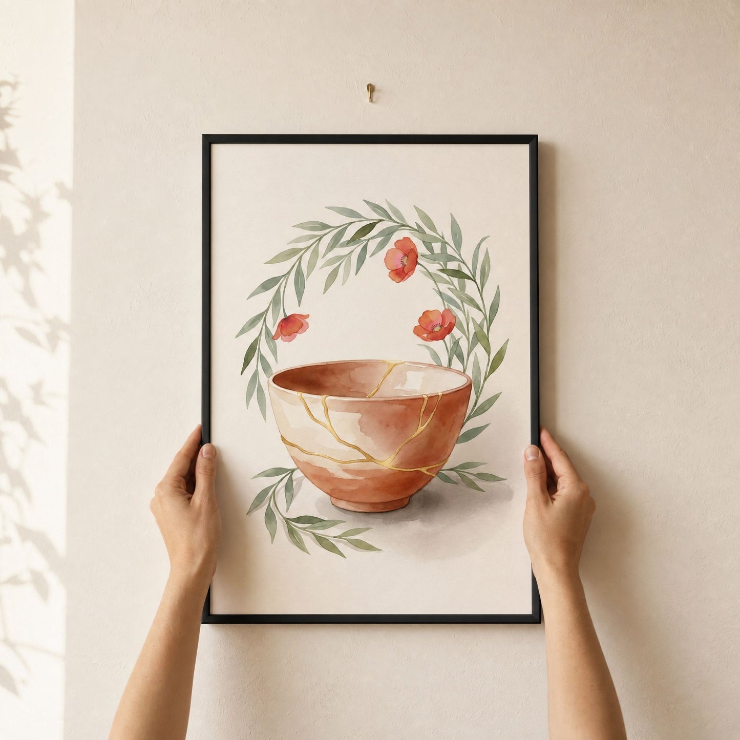 Hands lifting the framed kintsugi print onto a picture hook, arriving ready to hang with no framing needed