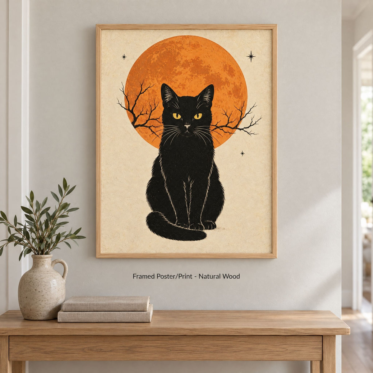 Vintage black cat art print in a natural wood frame above an oak console table