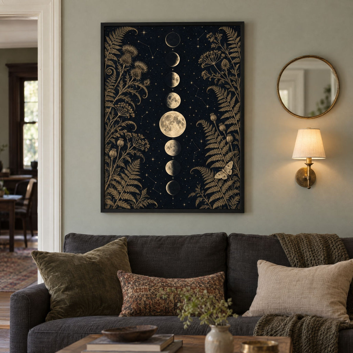 Moon phase wall art on a sage living room wall beside a round brass mirror and a glowing wall sconce