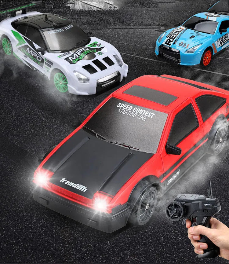 Three remote control cars on a racetrack with a hand holding a remote control.