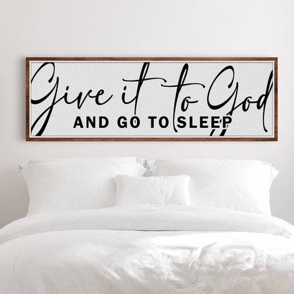 Long white canvas sign with large black script Give it to God and capitals And Go To Sleep, above a white bed