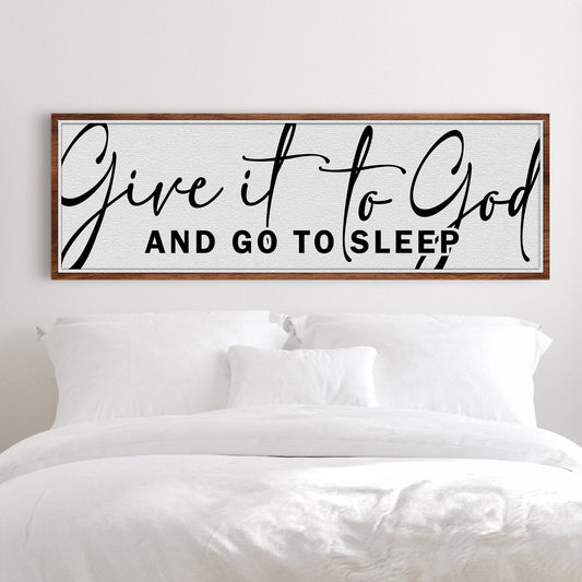 Long white canvas sign with large black script Give it to God and capitals And Go To Sleep, above a white bed