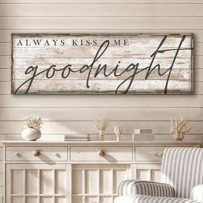 Long canvas sign reading Always Kiss Me Goodnight in gray script on whitewashed planks, above a white sideboard