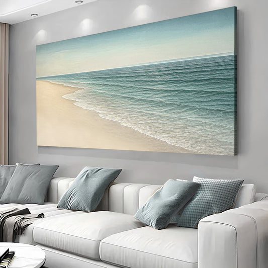 Teal waves rolling onto pale sand under a soft sky, printed on a canvas hanging above a white sofa