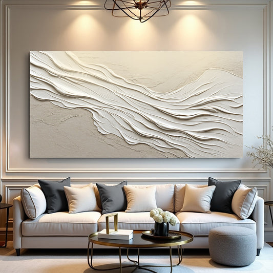 Canvas printed with white waves in a sculpted-plaster look on beige, hung wide above a grey sofa