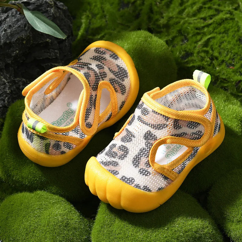 Pair of children's sandals with yellow soles and leopard print pattern on a green grass background