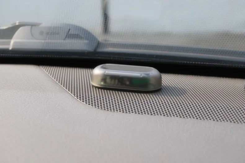 Solar powered decoy alarm LED installed on vehicle dash.