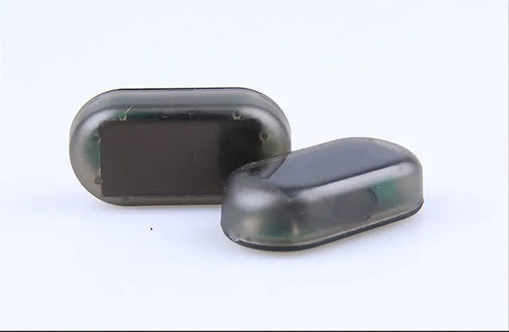 Compact simulated car alarm with adhesive mount on grille.