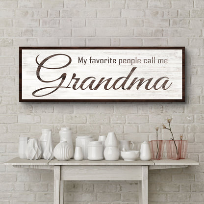 My Favorite People Call Me Grandma canvas sign in brown script on white, above a shelf of white vases on a brick wall