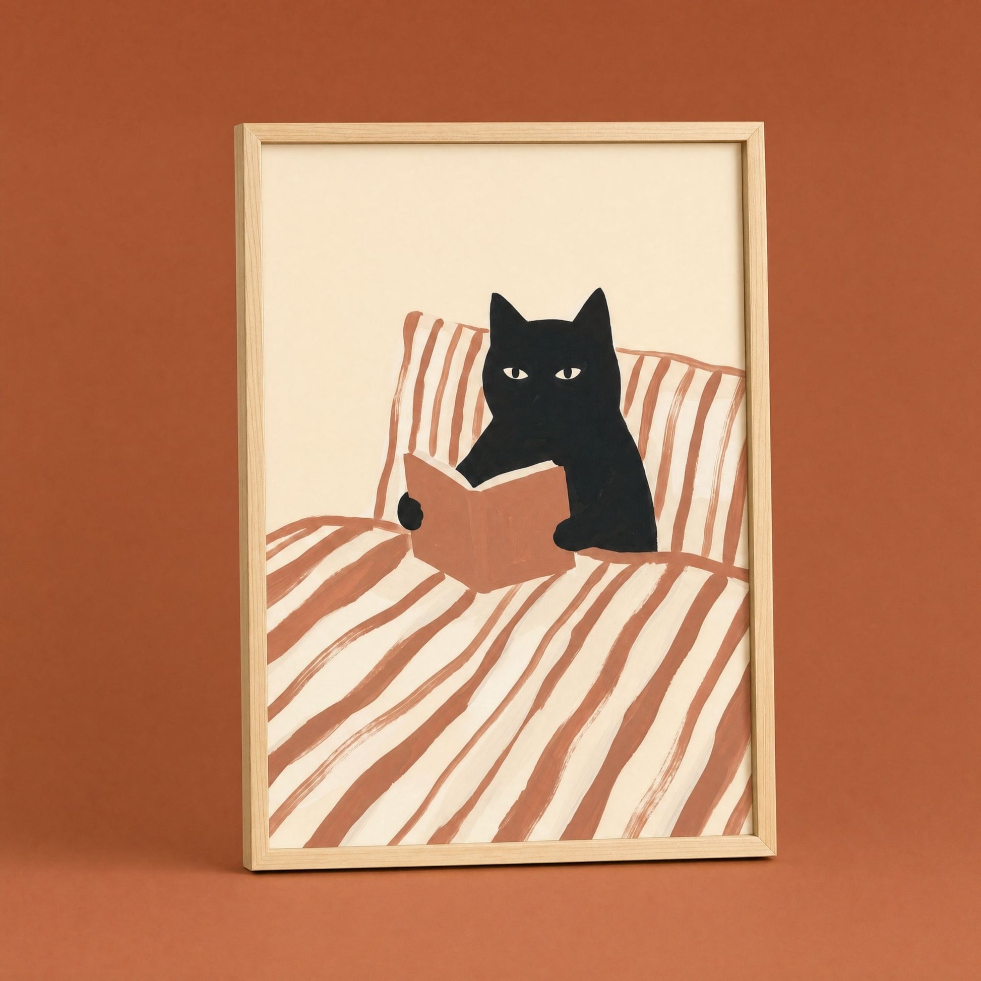 Cat reading poster in a natural wood frame on a terracotta wall, black cat with a book in striped bedding