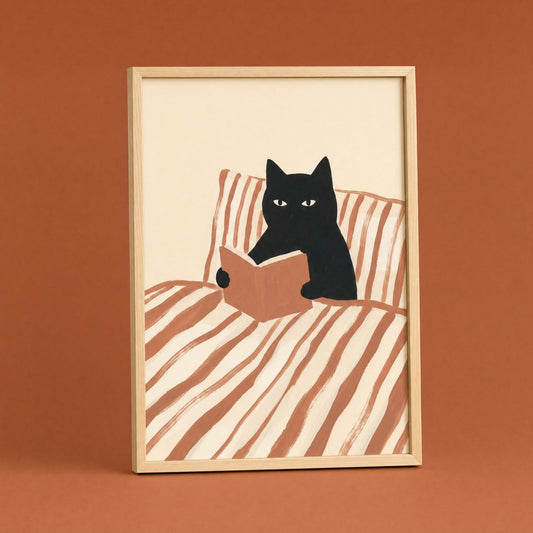 Cat reading poster in a natural wood frame on a terracotta wall, black cat with a book in striped bedding