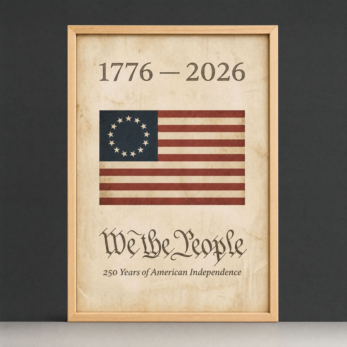 1776 American flag wall art in a natural wood frame - the We the People print with its Betsy Ross thirteen-star ring, shown upright on a plain dark studio ground