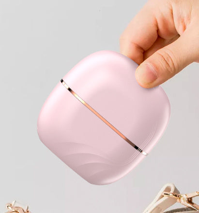 Pink Wireless Hair Straightening Comb with rose gold accents held by a hand on a light gray background