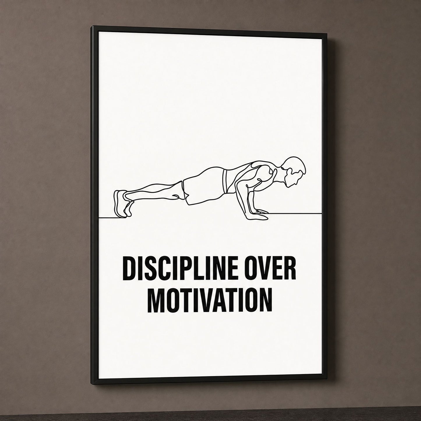 Discipline Over Motivation print in a black frame on a dark taupe wall, lit from the side