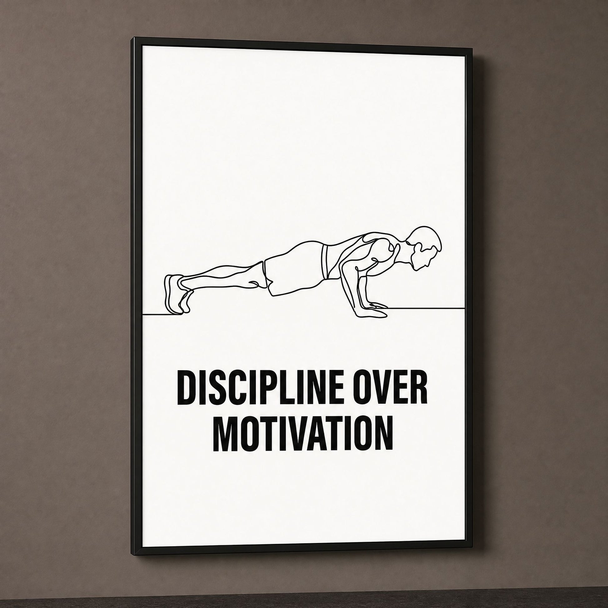 Discipline Over Motivation print in a black frame on a dark taupe wall, lit from the side