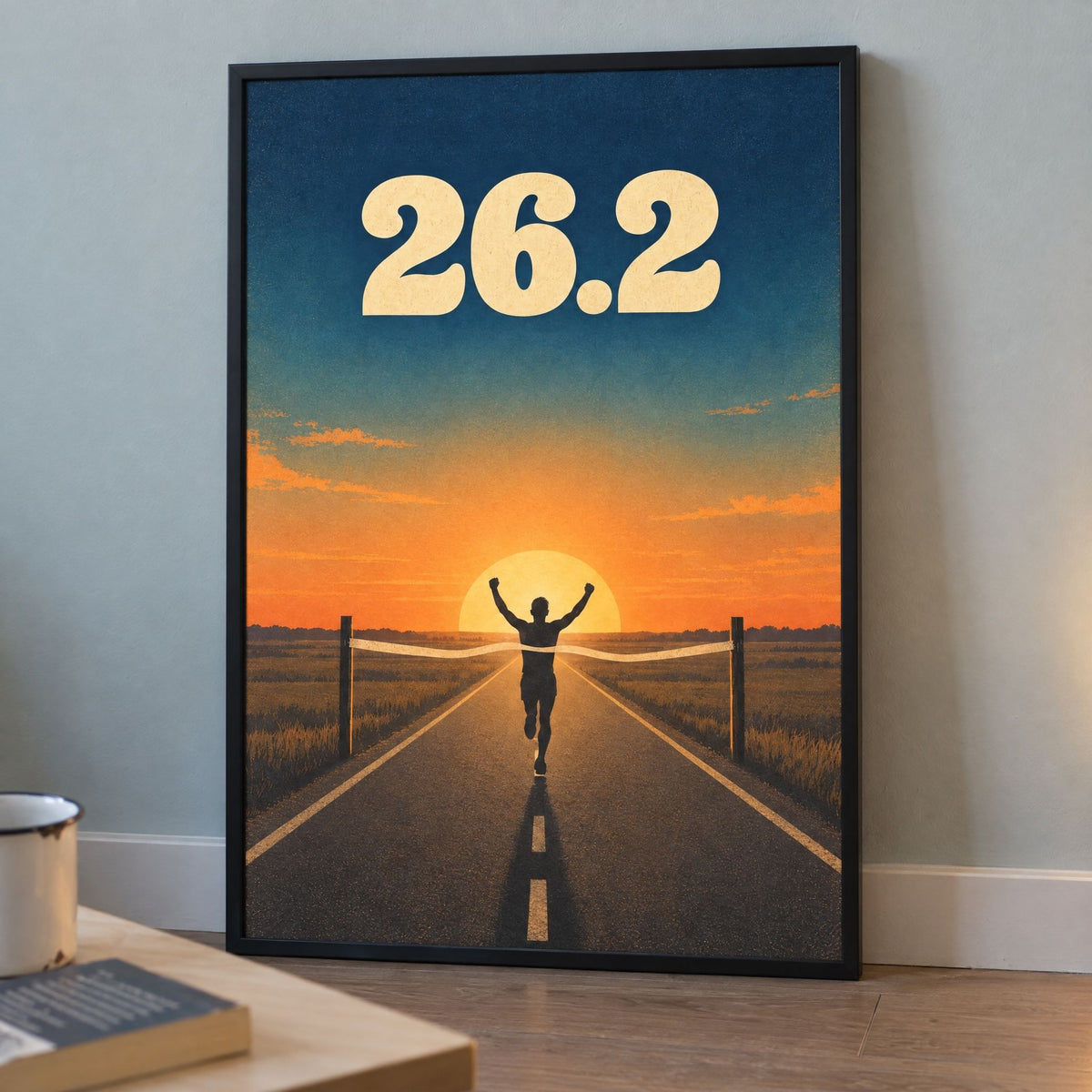 Black framed 26.2 marathon print leaning against a home office wall beside the desk, sunrise running poster