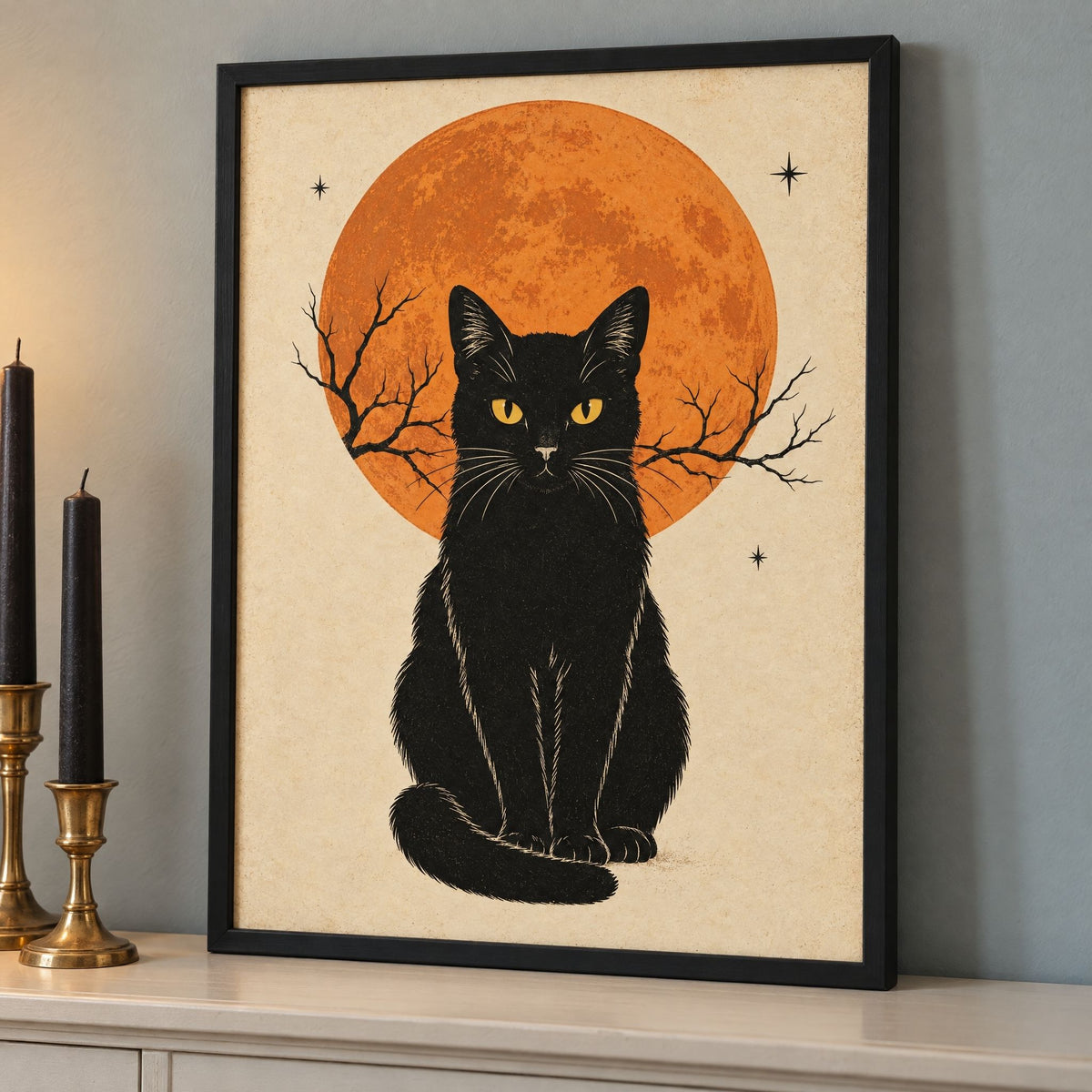 Framed black cat Halloween print leaning on a dining room sideboard beside two black taper candles