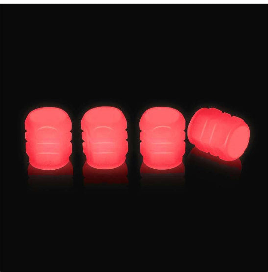 Set of four neon red photoluminescent tire valve caps on black background