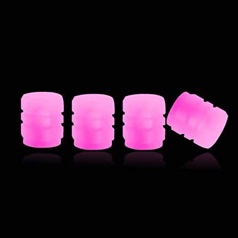 Set of four neon pink photoluminescent tire valve caps on black background