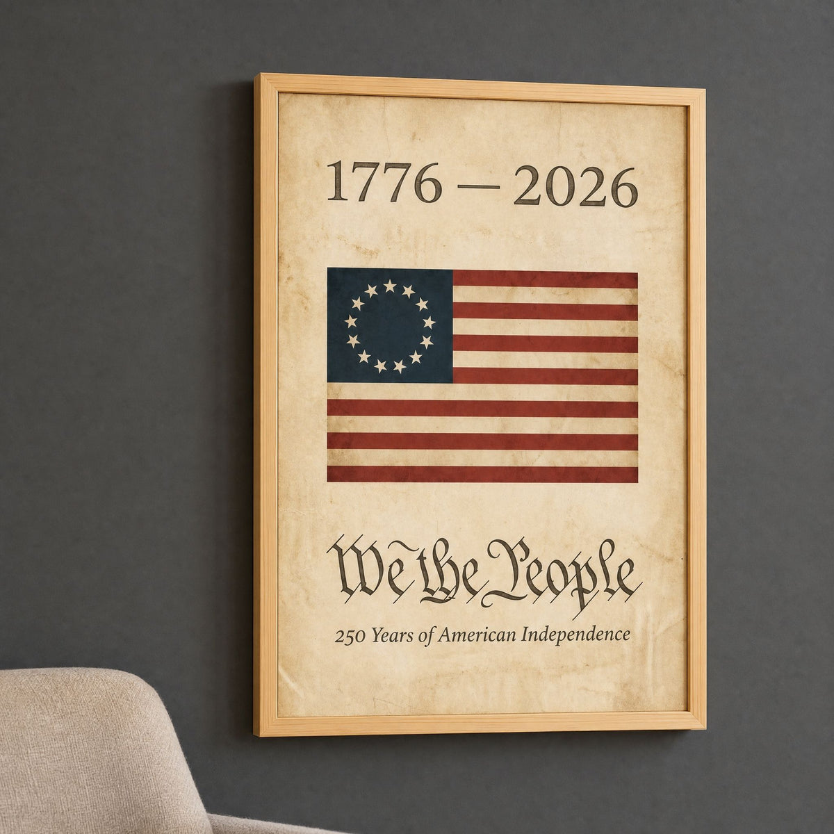 1776 We the People American flag print in a natural wood frame, hung on a deep charcoal wall above an oatmeal armchair