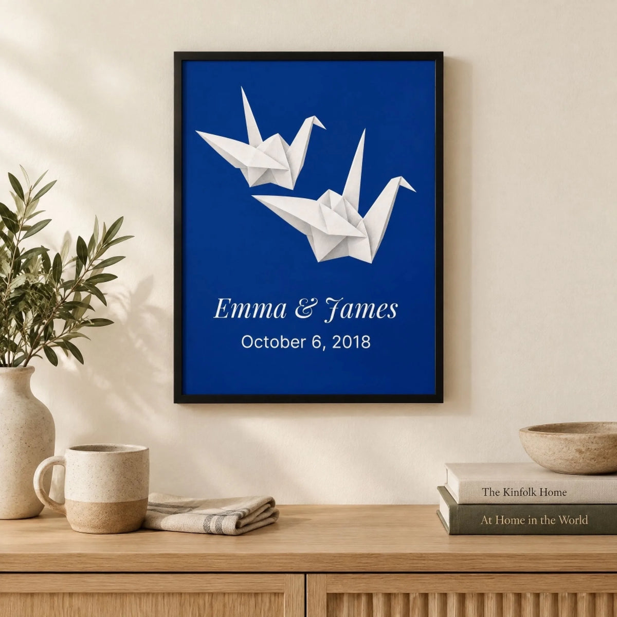 Two paper cranes print hanging above a console, sized to the wall in a first home living room