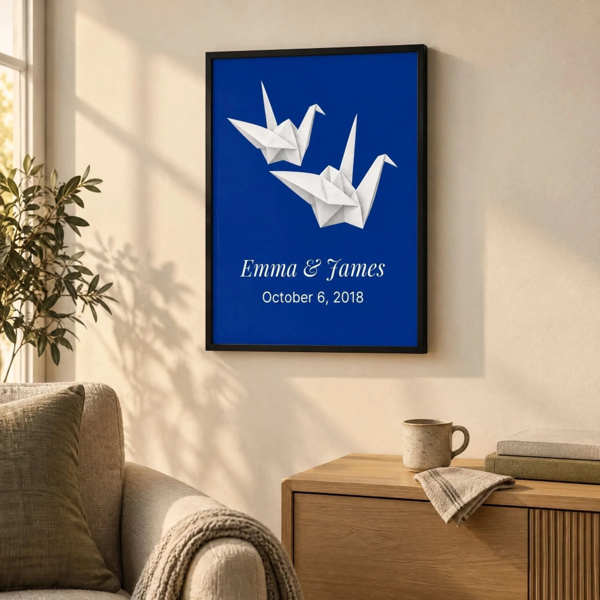 Paper cranes anniversary print anchoring a calm living room corner with a linen chair and oak console
