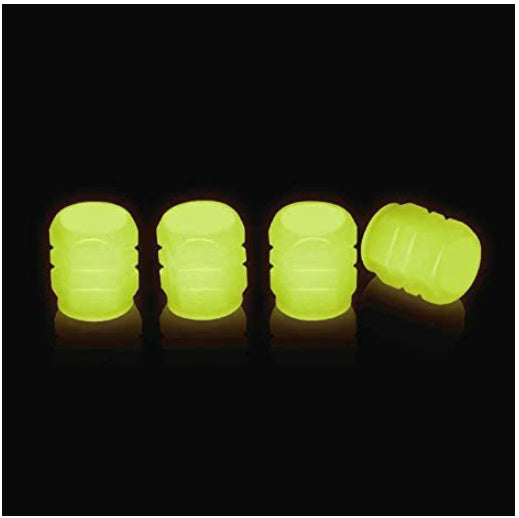 Set of four neon yellow photoluminescent tire valve caps on black background