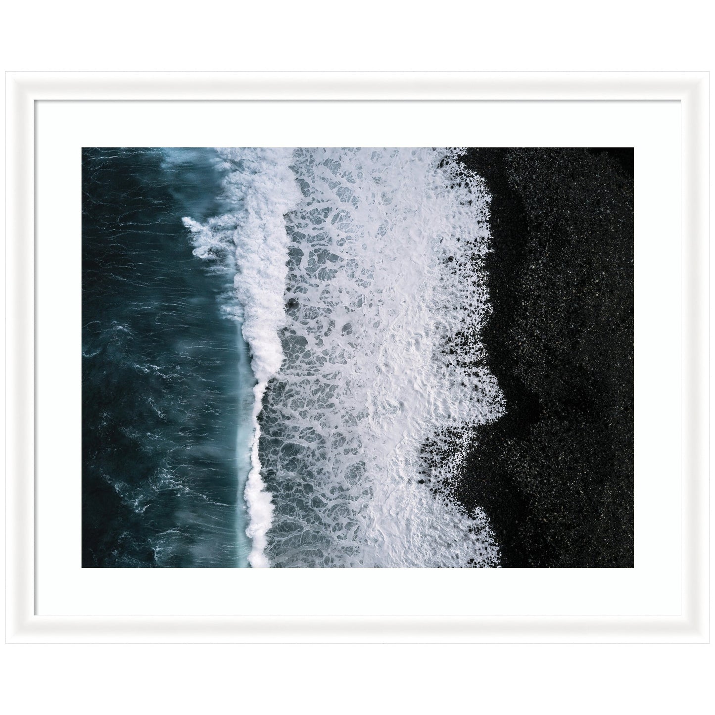 Framed coastal wall art of ocean waves on a black beach in Iceland, deep blue water and white foam