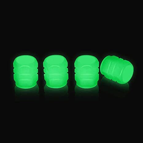 Set of four neon green photoluminescent tire valve caps on black background
