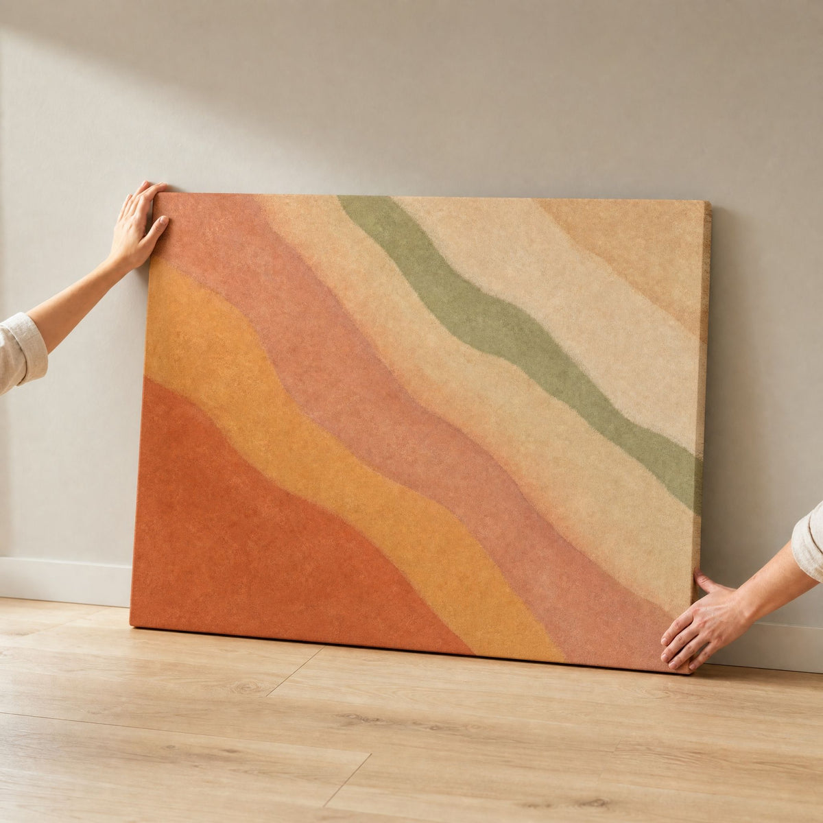 Two hands holding the large canvas upright on a wood floor to show its scale