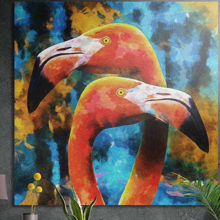Two coral flamingos over a blue and gold brushy background, brushed aluminum wall art on a dark wall behind plants
